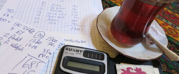 Rechnungen, Taschenrechner und ein Glas Tee