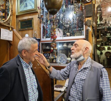 Necati mit Ali Bey, einem älteren Mann mit weissem Bart und kariertem Hemd inmitten von antiken Kupfergegenständen
