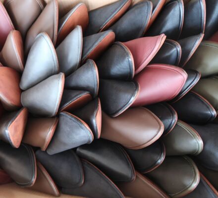 Eine Kartonschachtel voller Babouches-Schuhe in Schwarz, Grau, Bordeaux und Olivgrün