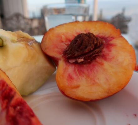 ein halber Pfirsich und eine angeschnittene Birne auf Marmortisch im Abendlicht
