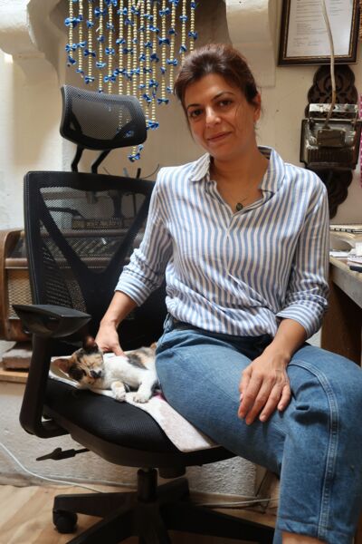 Azize, die junge Kräuterhändlerin sitzt auf einem Bürostuhl mit einer Katze.